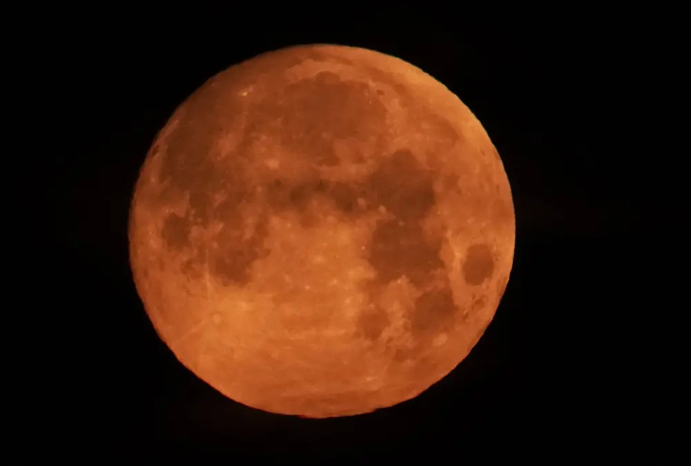 A real photograph of the Moon partially covered by Earth’s shadow during a lunar eclipse, with a dark curved shadow across the lunar surface