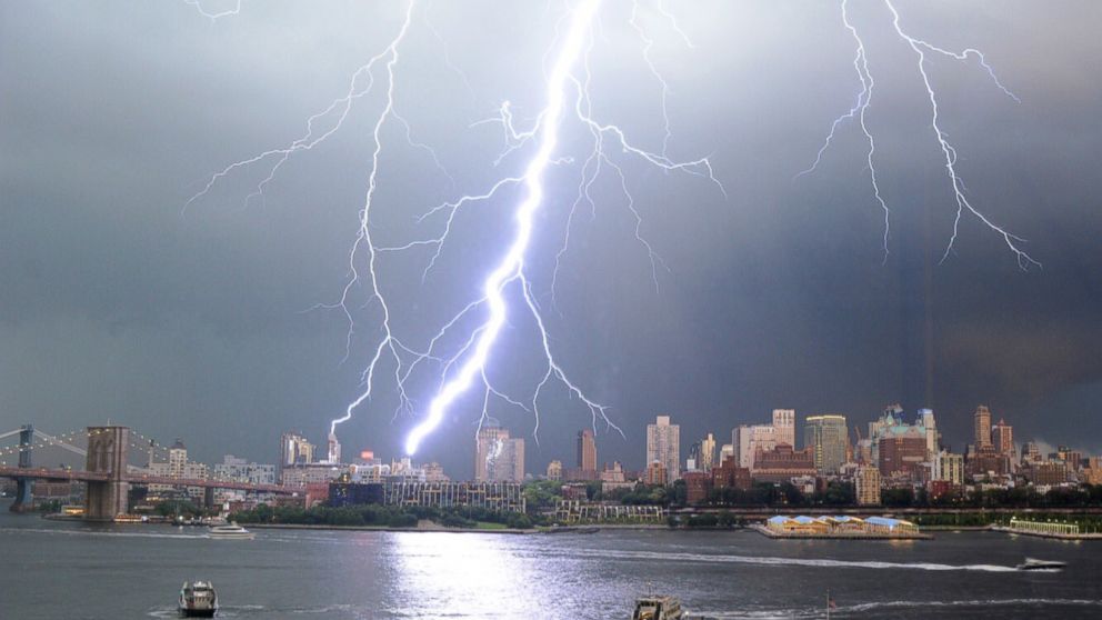 Lightning from a distant thunderstorm above a city skyline at night, with dark clouds and scattered lights